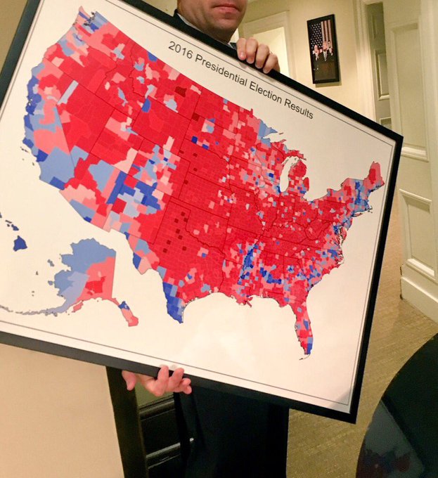 Person holds map of 2016 presidential election results colored red and blue by county